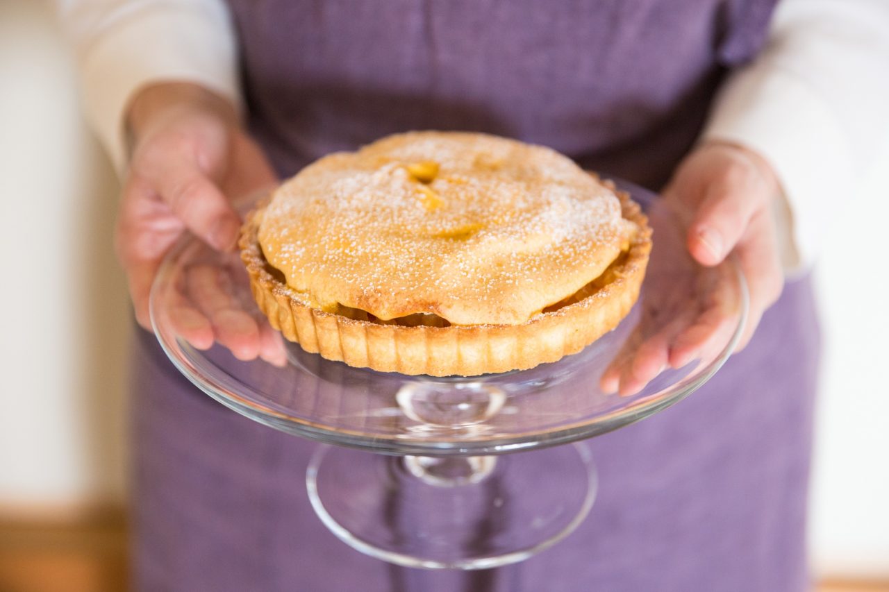ガラスの器に入ったタルトケーキを持って