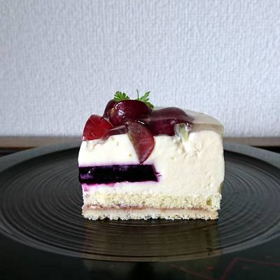 黒くて丸く平らなお皿に乗せた赤葡萄と白ワインのムースケーキ