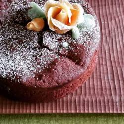 バラ（菓子）がデコレーションされたガトーショコラが木の器にのっています。