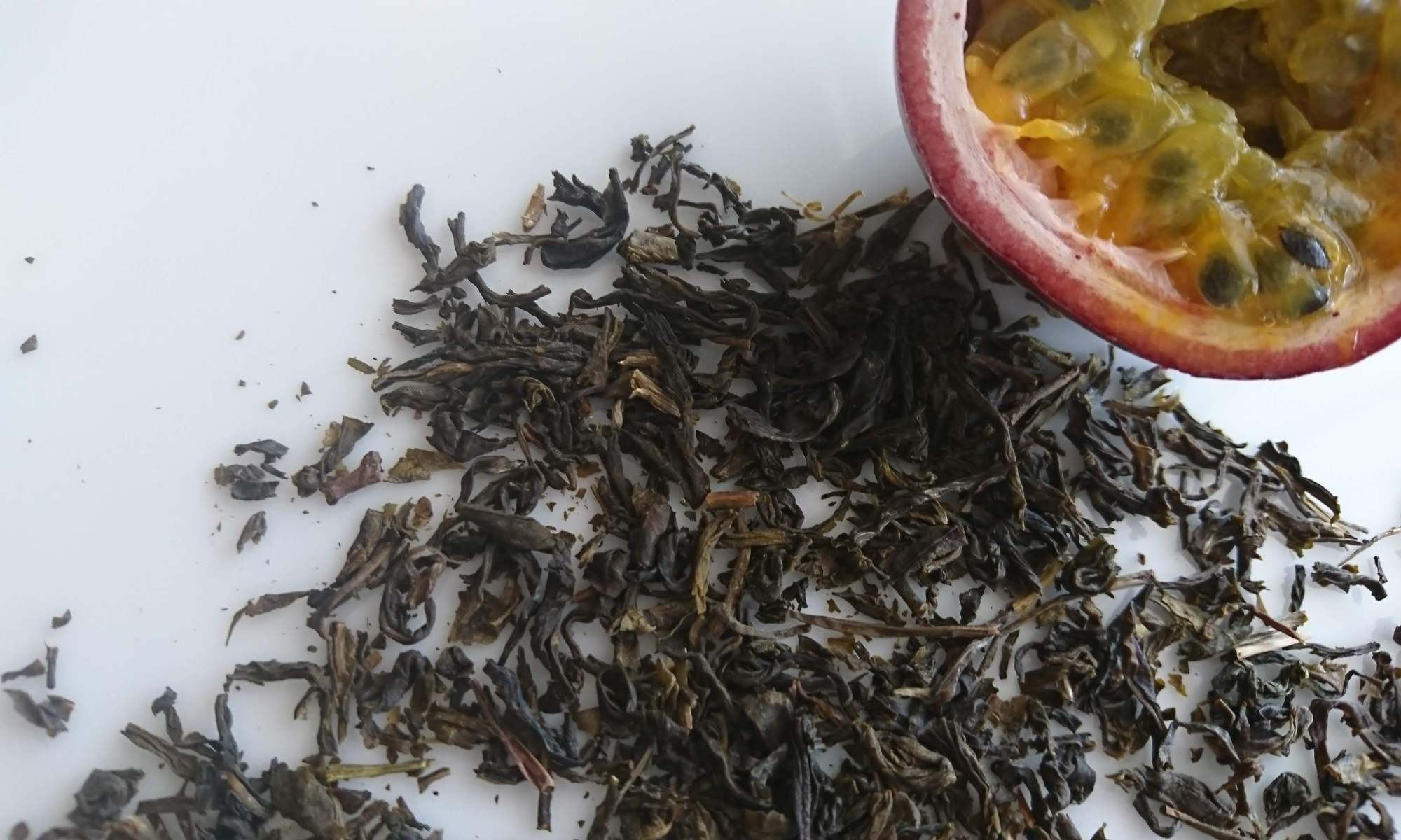 白皿の上二ジャスミン茶葉とカットされたパッションフルーツ