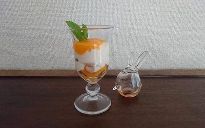 白いプリンとマンゴーソース・ミントがグラスに盛り付けられています。