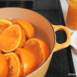 半割のオレンジが大鍋に水と共に入り火にかけています