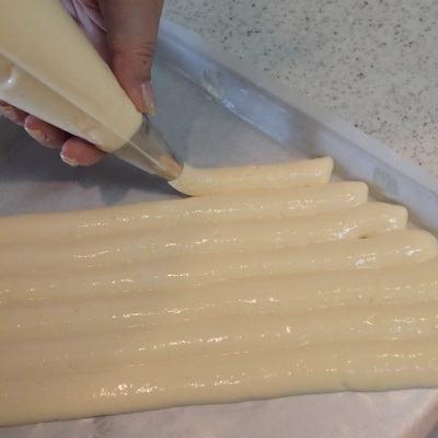 天板の上に絞り袋に入った生地を絞っています。