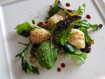 白いお皿の上に緑の野菜とお肉と桃が盛り付けられています。