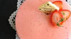 漆黒盆の上にピンクの苺ムースケーキのホールがあります