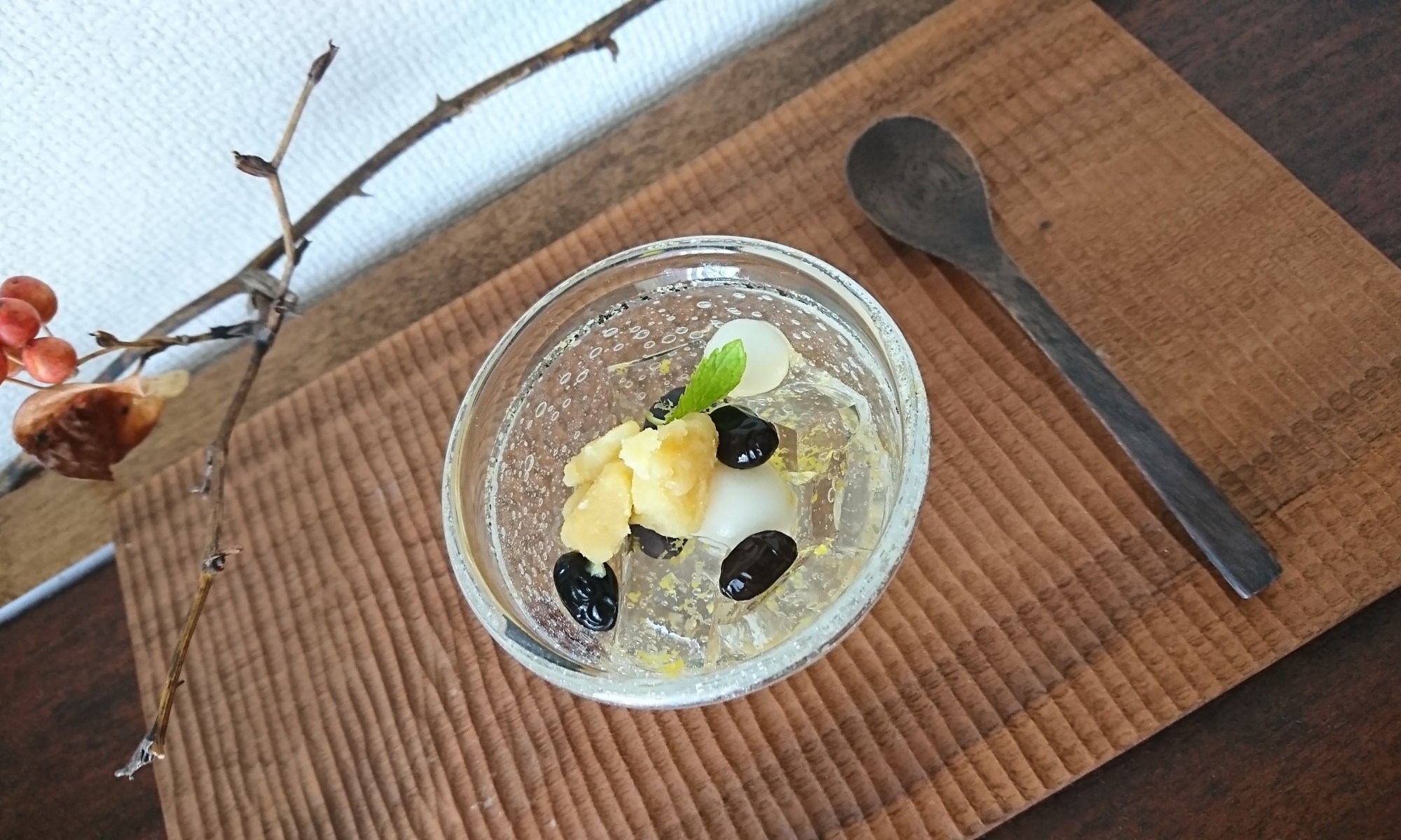柚子ゼリーと黒豆・白玉団子・栗きんとんが盛り付けられたガラスの器が木盆に