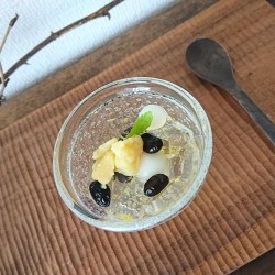 柚子ゼリーと黒豆・白玉団子・栗きんとんが盛り付けられたガラスの器が木盆に