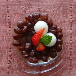 ガラスの器にぜんざいと丸い白玉団子、苺とミントが盛り付けられています