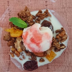 ガラスの器にグラノーラとマーブル状の苺アイスと甘酒が盛り付けられています