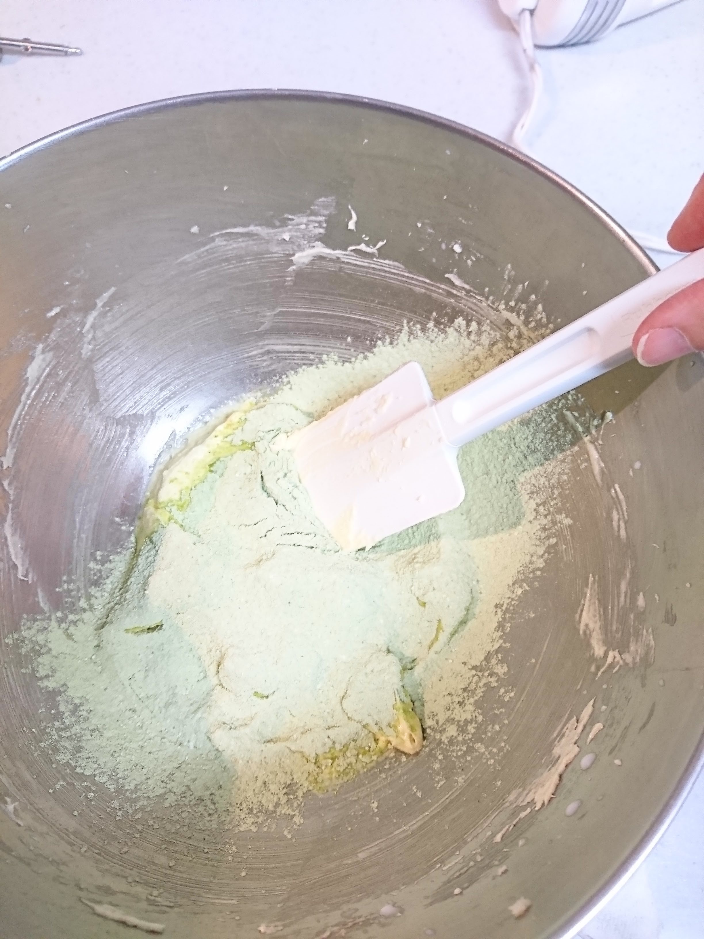生地の入ったボウルに粉類を入れボムベラで混ぜている。