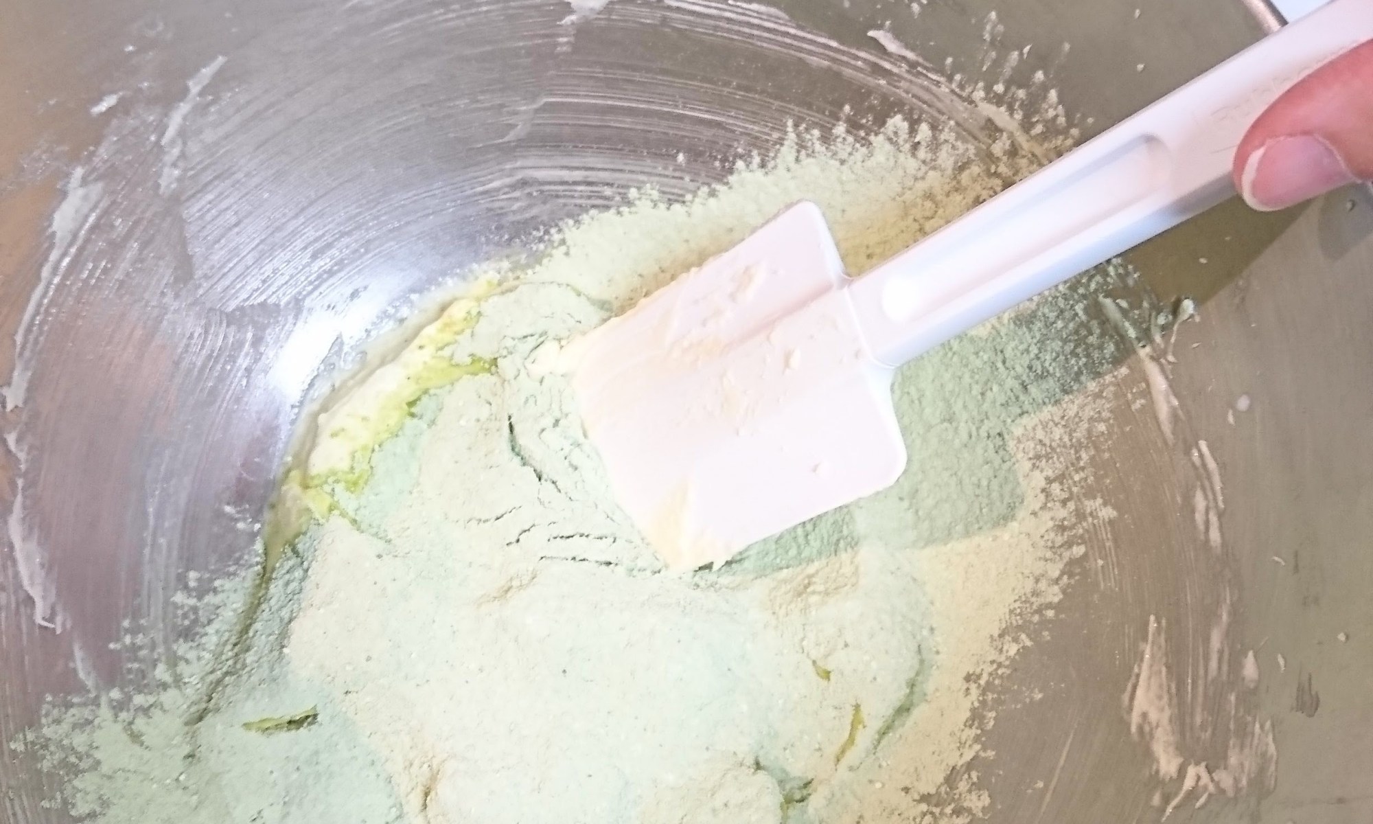 生地の入ったボウルに粉類を入れボムベラで混ぜている。
