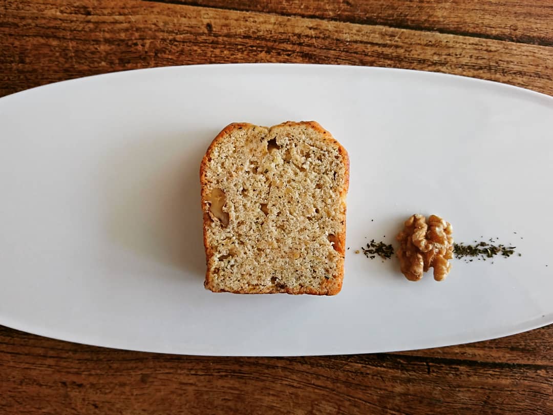 白皿の上にカットされたパウンドケーキと胡桃と茶葉が盛り付けられている