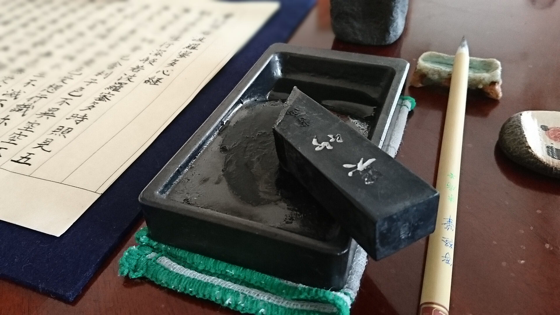 硯の上に墨が乗り横には筆と写経した半紙が並んでいます。