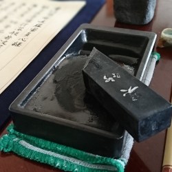 硯の上に墨が乗り横には筆と写経した半紙が並んでいます。