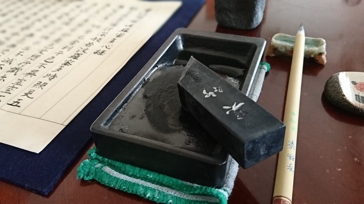 硯の上に墨が乗り横には筆と写経した半紙が並んでいます。