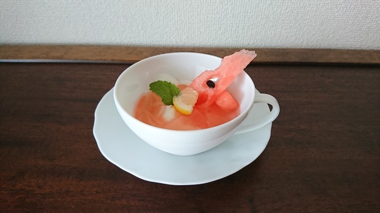 白いカップ＆ソーサーにスイカのジュレがかかった杏仁豆腐が盛り付けられています。