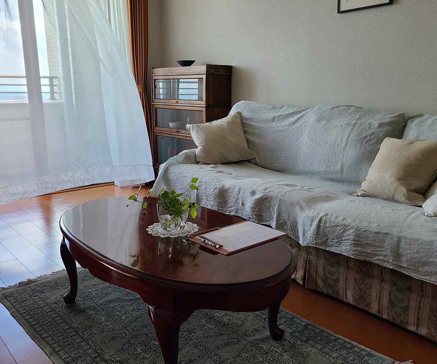 風で揺れるカーテン、ソファー＆テーブルが置かれたリビング