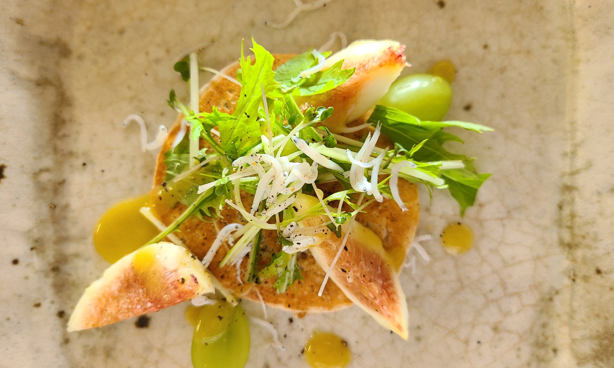 陶器にパンケーキと水菜やしらす、無花果、葡萄が盛り付けられています。