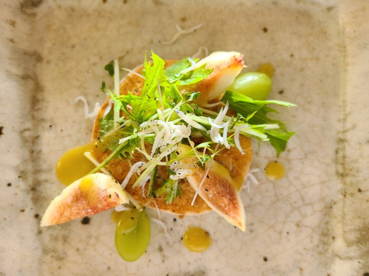 陶器にパンケーキと水菜やしらす、無花果、葡萄が盛り付けられています。