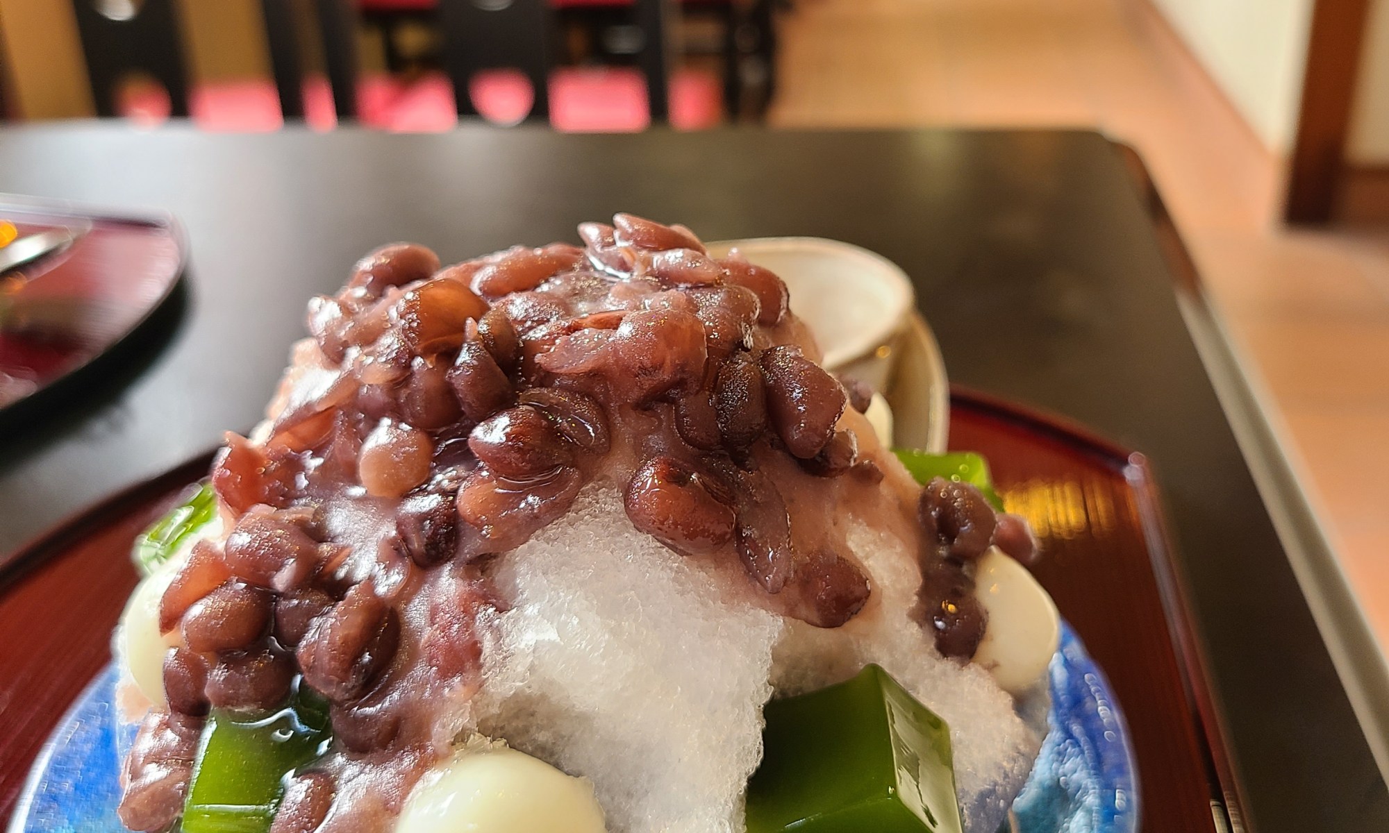 ガラスの器一杯に餡子と抹茶ゼリー白玉がのったぜんざい氷