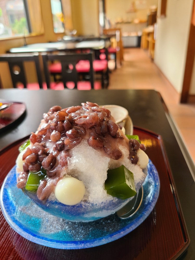 ガラスの器一杯に餡子と抹茶ゼリー白玉がのったぜんざい氷