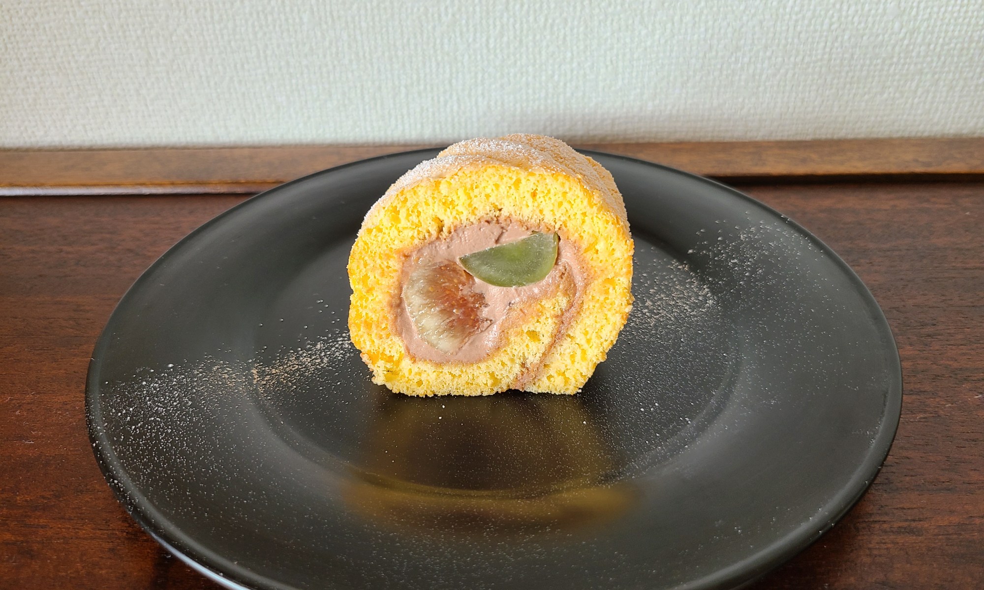 漆黒の器に秋の果実を巻いたロールケーキが1カット。