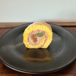 漆黒の器に秋の果実を巻いたロールケーキが1カット。