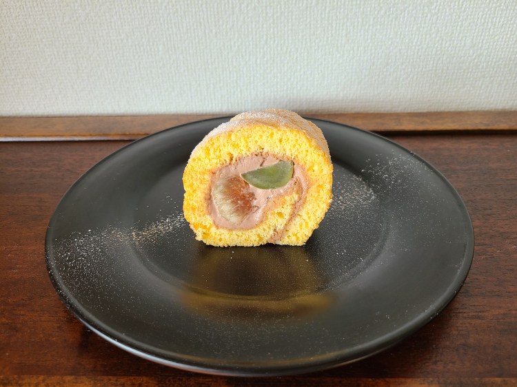 漆黒の器に秋の果実を巻いたロールケーキが1カット。