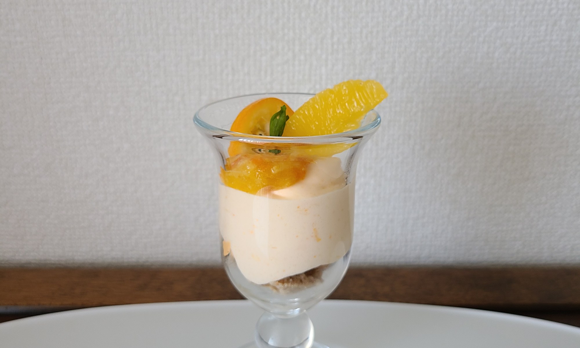 グラスに入ったオレンジのムースの上にオレンジピューレや生の果肉がデコレート