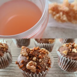 ガラス瓶に入ったピンク色のシロップとラックに並ぶカップケーキ