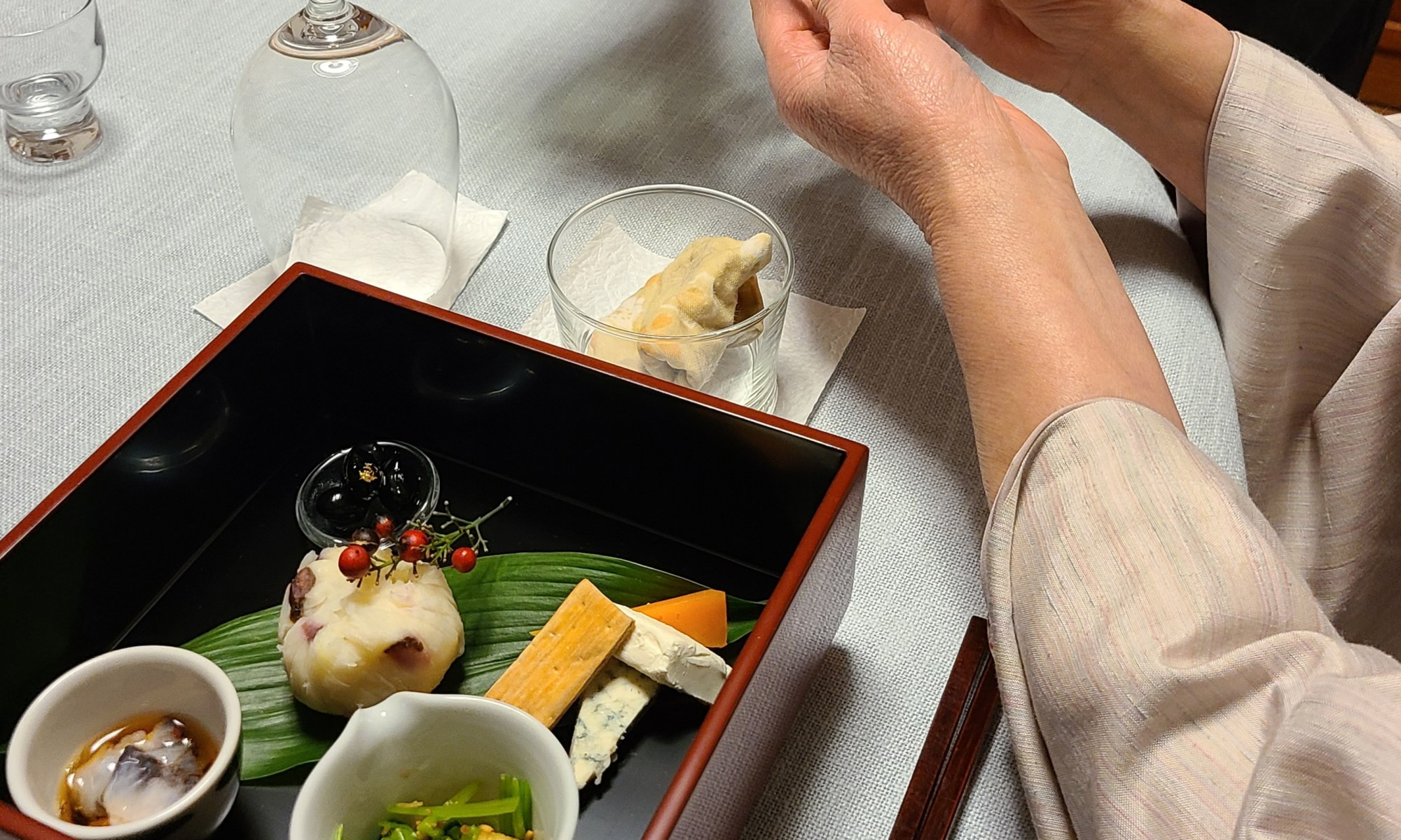 テーブルにお重が並びお酒を注いでいる風景