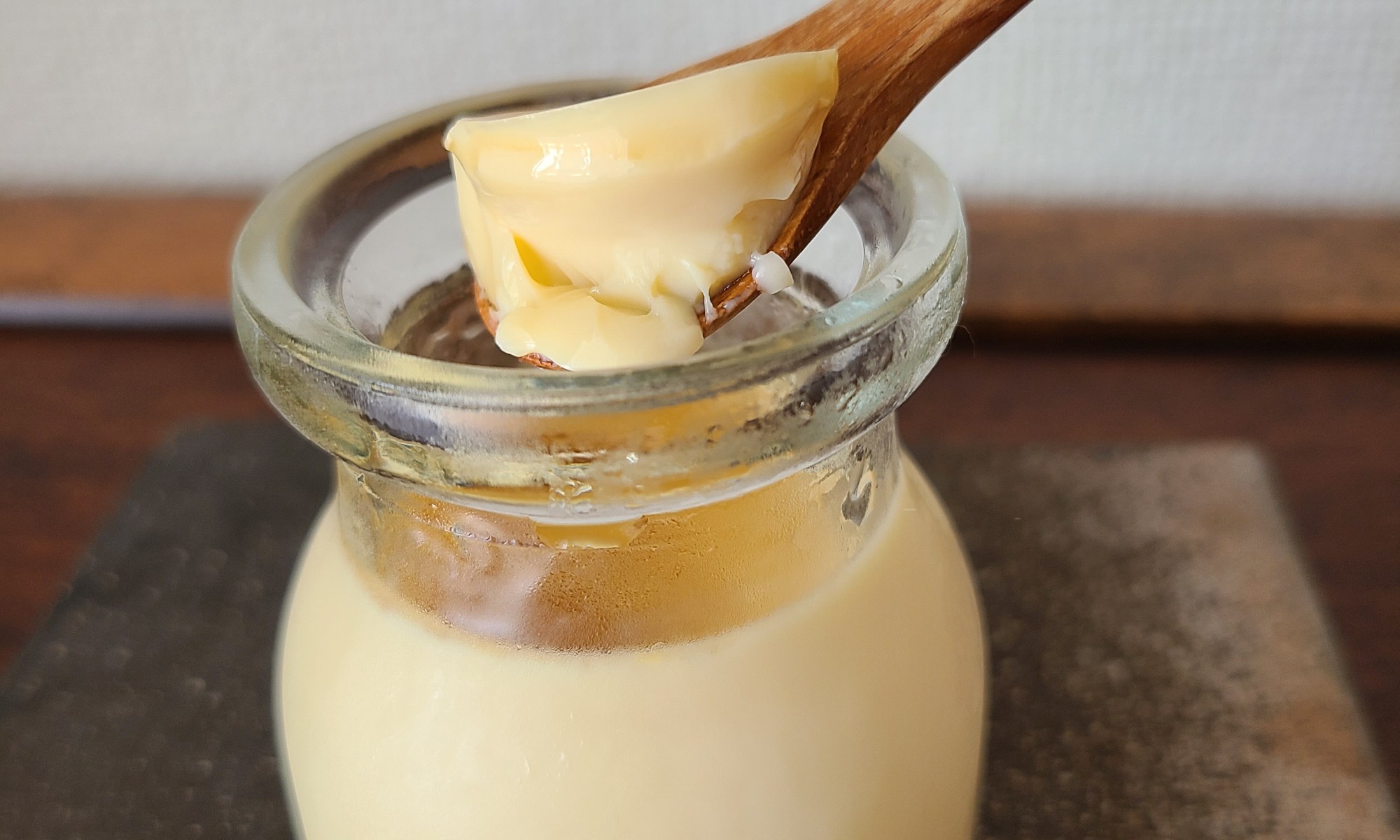 蒸しあがったプリン(瓶)をスプーンで掬い上げている