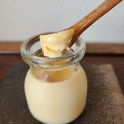 蒸しあがったプリン(瓶)をスプーンで掬い上げている