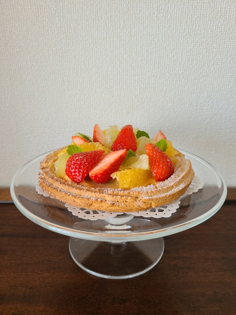 ガラスのケーキスタンドにフルーツタルトがあります