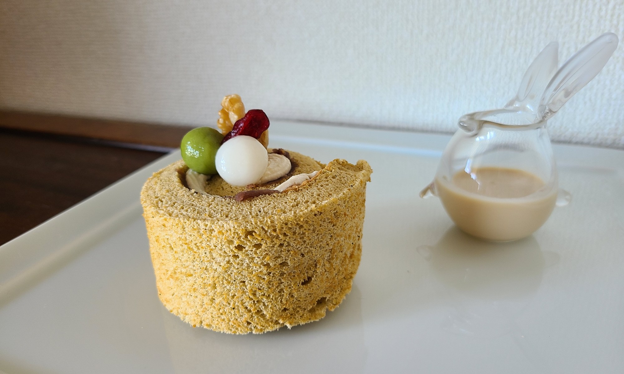 白皿の上にカットしたロールケーキとソースの入ったガラス容器が並んでいます