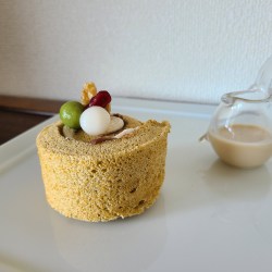 白皿の上にカットしたロールケーキとソースの入ったガラス容器が並んでいます