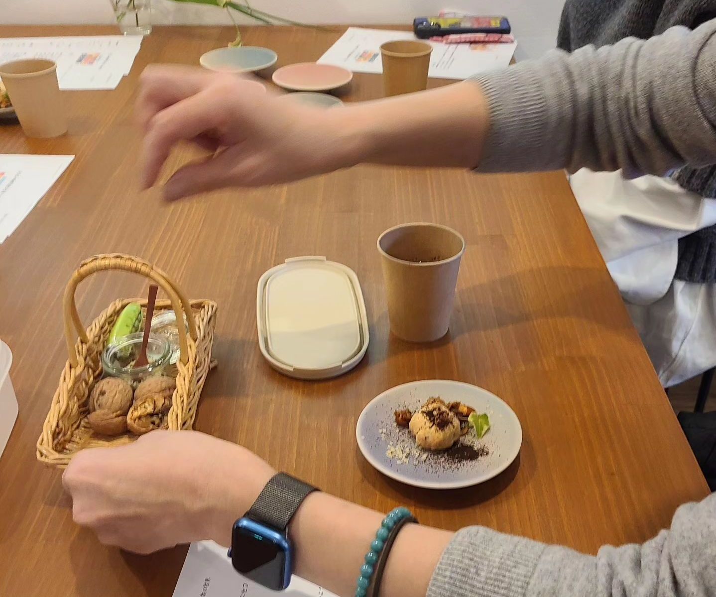 テーブルに菓子が盛られた器たちを囲む人たち