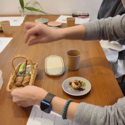 テーブルに菓子が盛られた器たちを囲む人たち